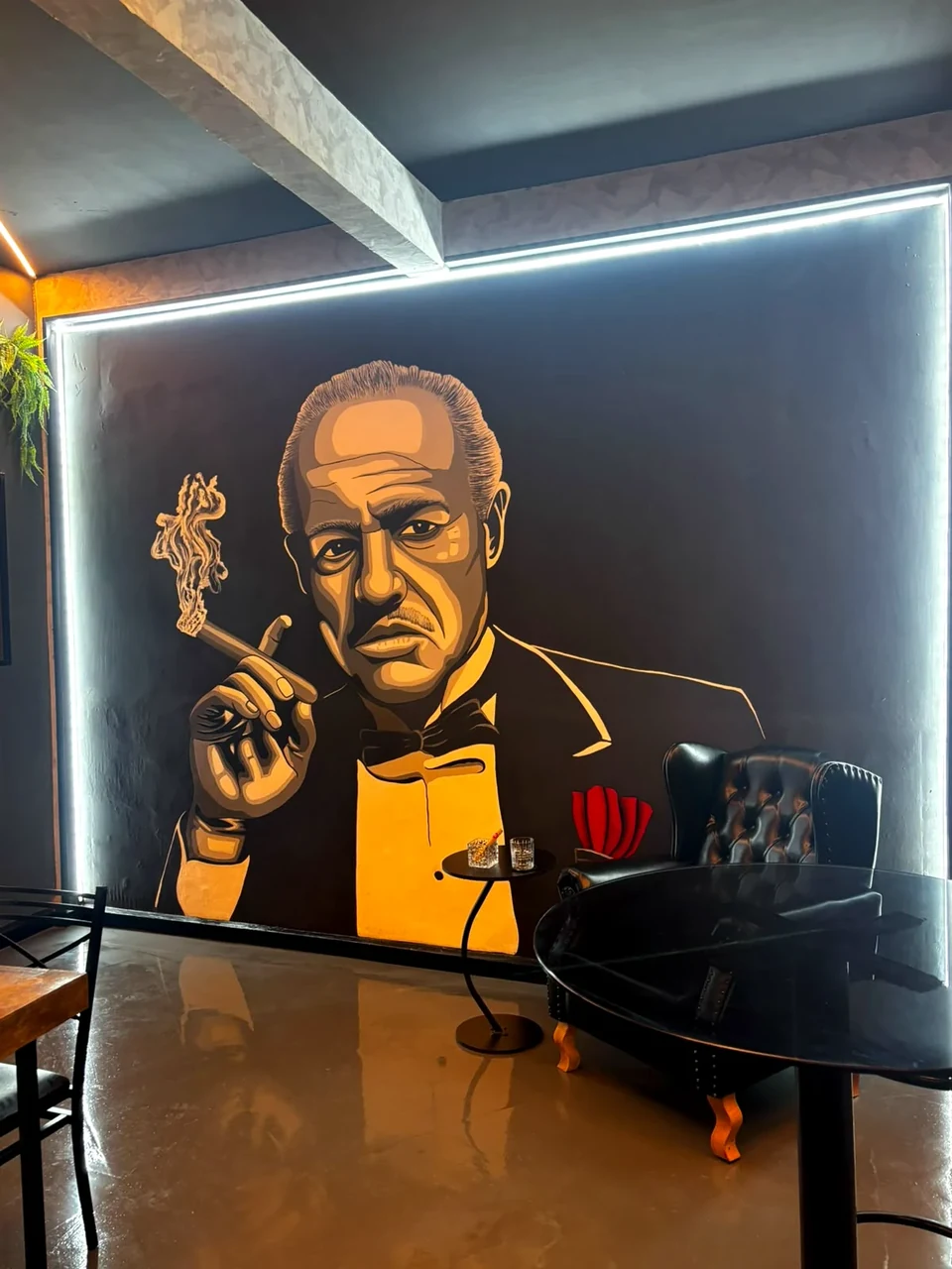 Ambiente interno do O Poderoso Pub com mural temático e poltrona de couro
